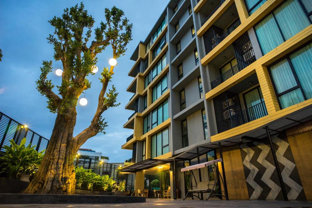 ein Apartmenthaus mit einem Baum davor in der Unterkunft Sanae' Hotel Nimman in Chiang Mai