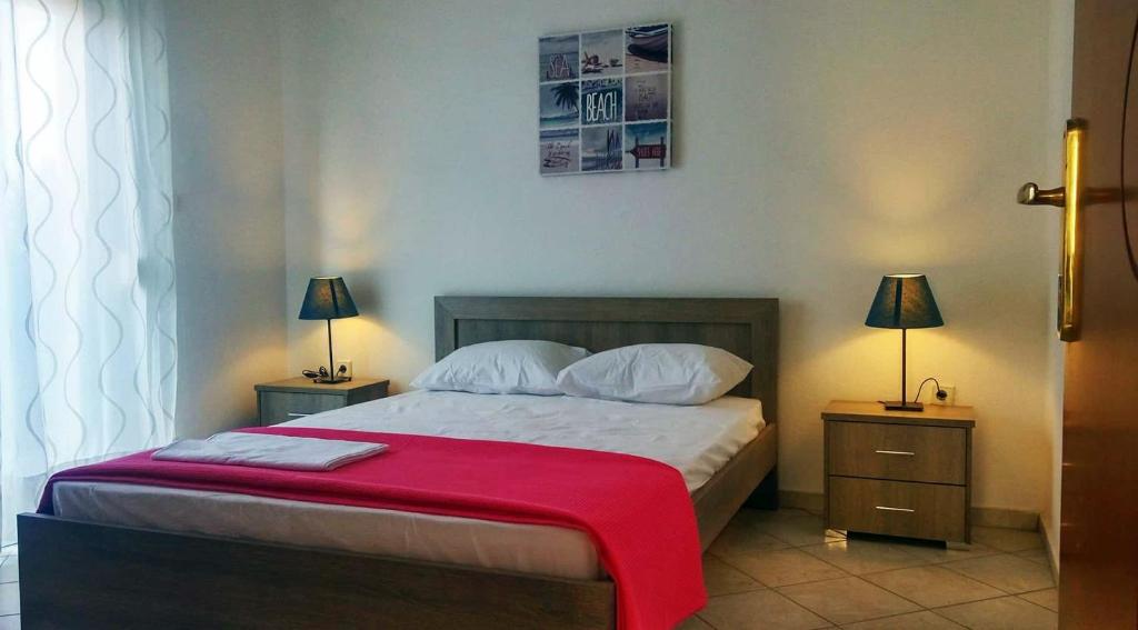a bedroom with a bed with a red blanket on it at Roses RT apartments Skioni I in Nea Skioni
