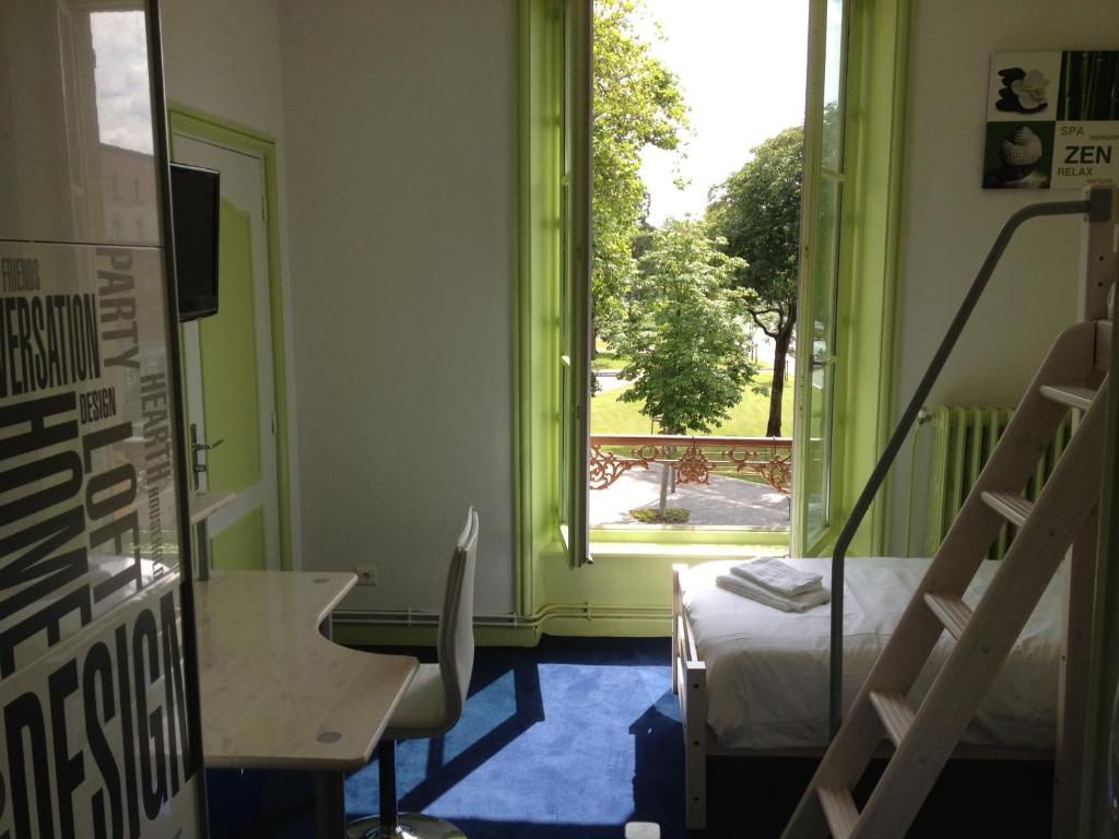 een kamer met een groene deur, een bed en een raam bij Hotel Bar Restaurant Couleurs Sud in Charleville-Mézières