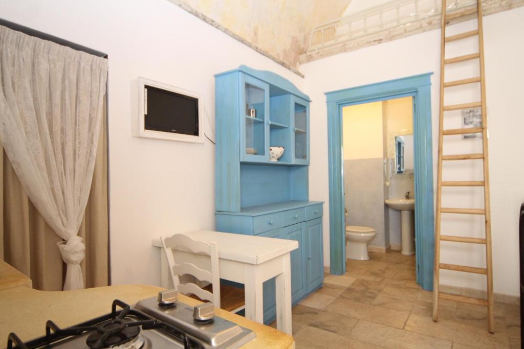 Habitación con armario azul, mesa y baño. en Appartamento la Corte Azzurra en Alliste