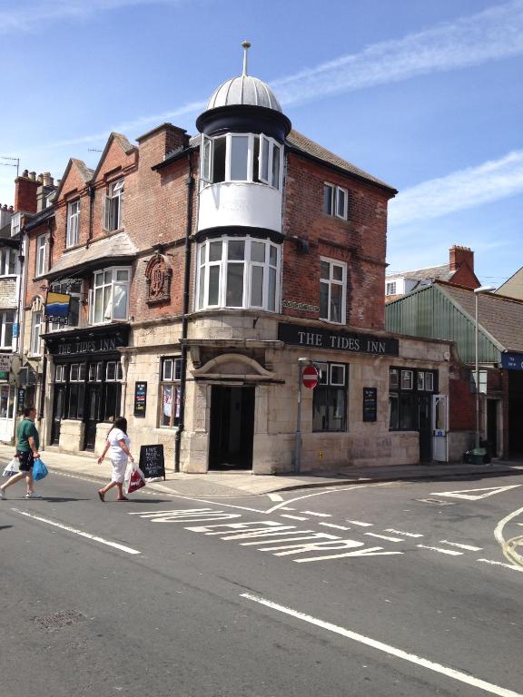 ein altes Gebäude mit einem Turm an der Ecke einer Straße in der Unterkunft The Tides Inn in Weymouth