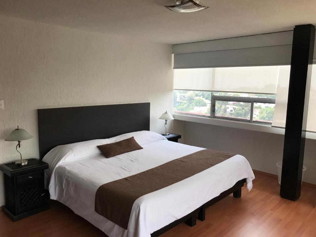 a bedroom with a large bed and a window at Bosque de Magnolias 93 in Mexico City