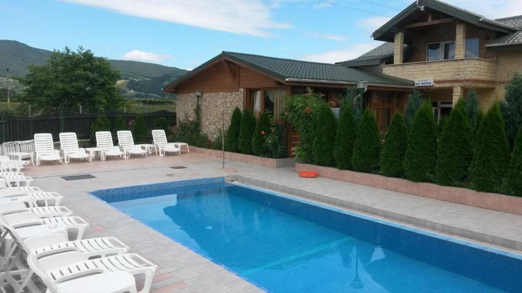 una piscina con sedie bianche e una casa di Pensiunea Lory a Piatra Neamţ
