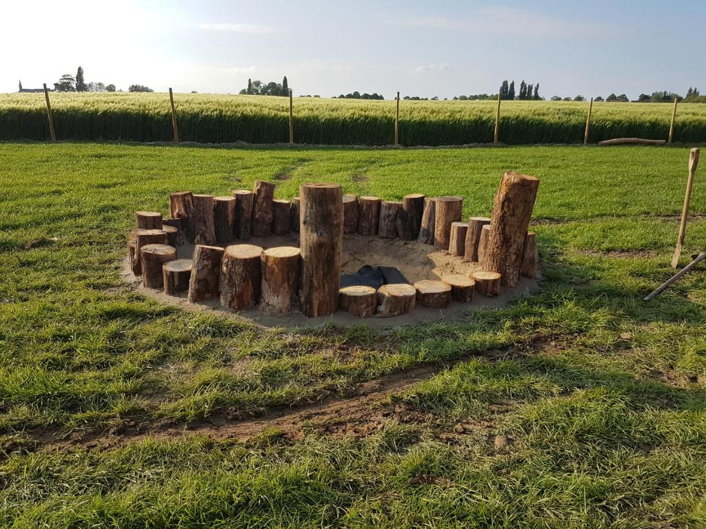 a fire pit made out of logs in a field at Holiday home Het Zeugekot in Beveren