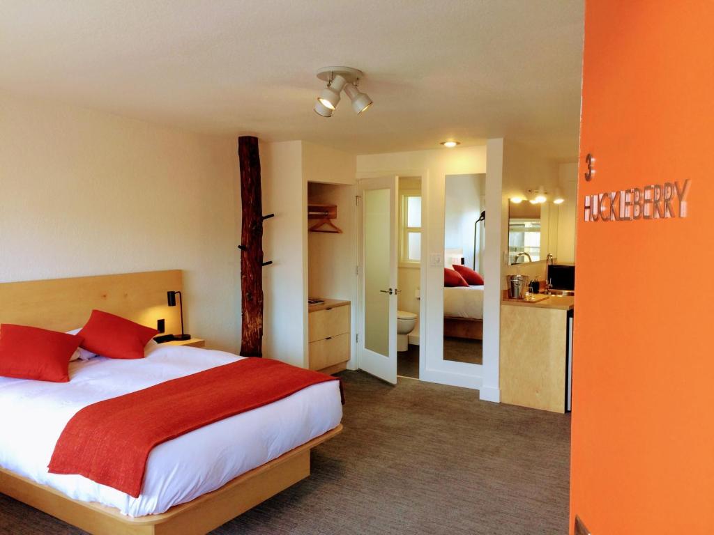 a bedroom with a bed with red pillows and a kitchen at Heliotrope Hotel in Bellingham