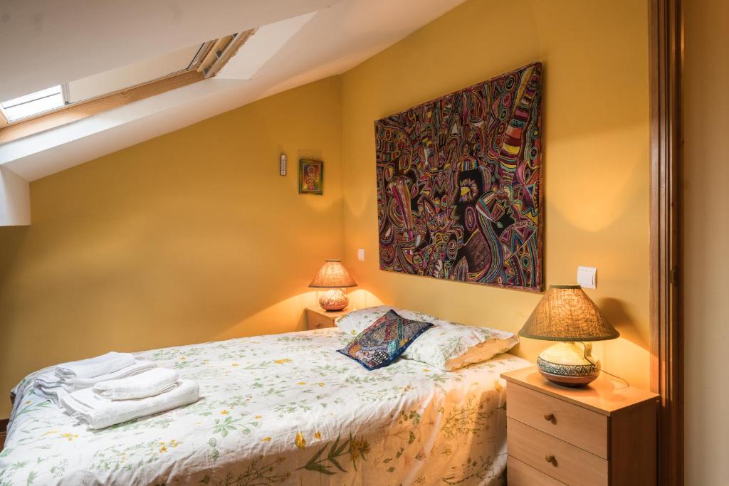 1 dormitorio con 1 cama con una pintura en la pared en Casa el Cuco, en Navarredonda de Gredos