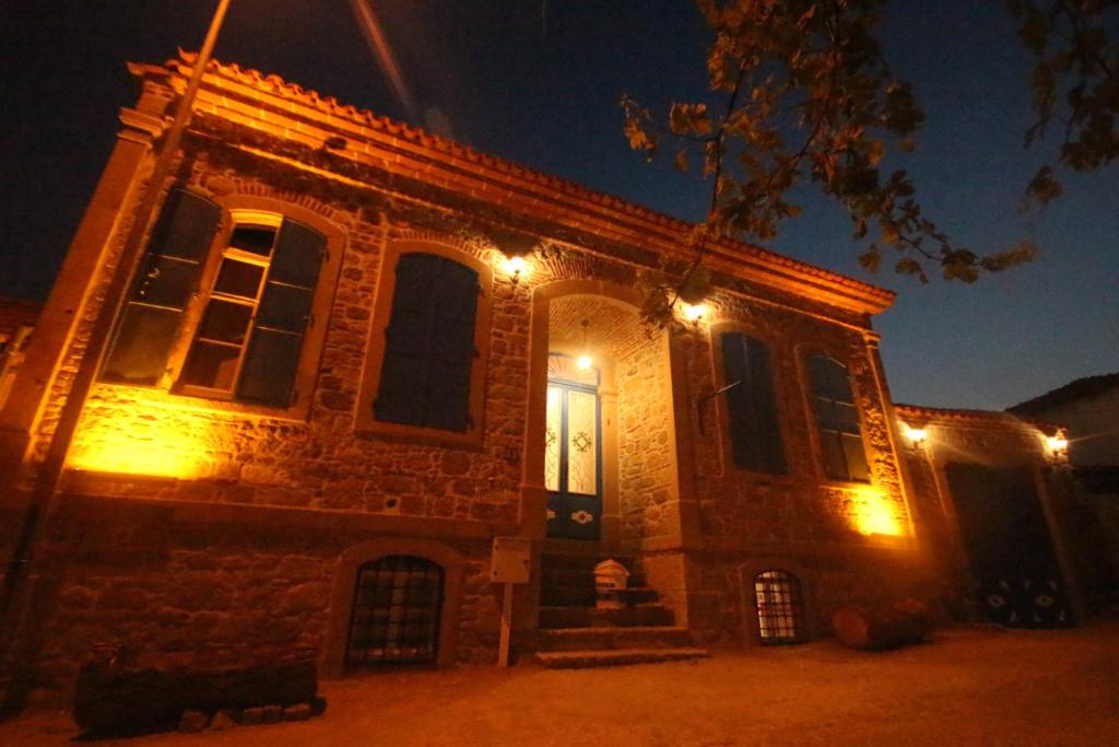 una vieja casa de ladrillo con luces encendidas por la noche en TAŞKONAK en Bergama