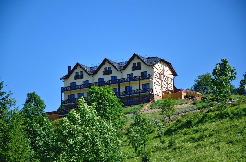 a large building on top of a hill with trees at Penzion Na Vršku in Branná