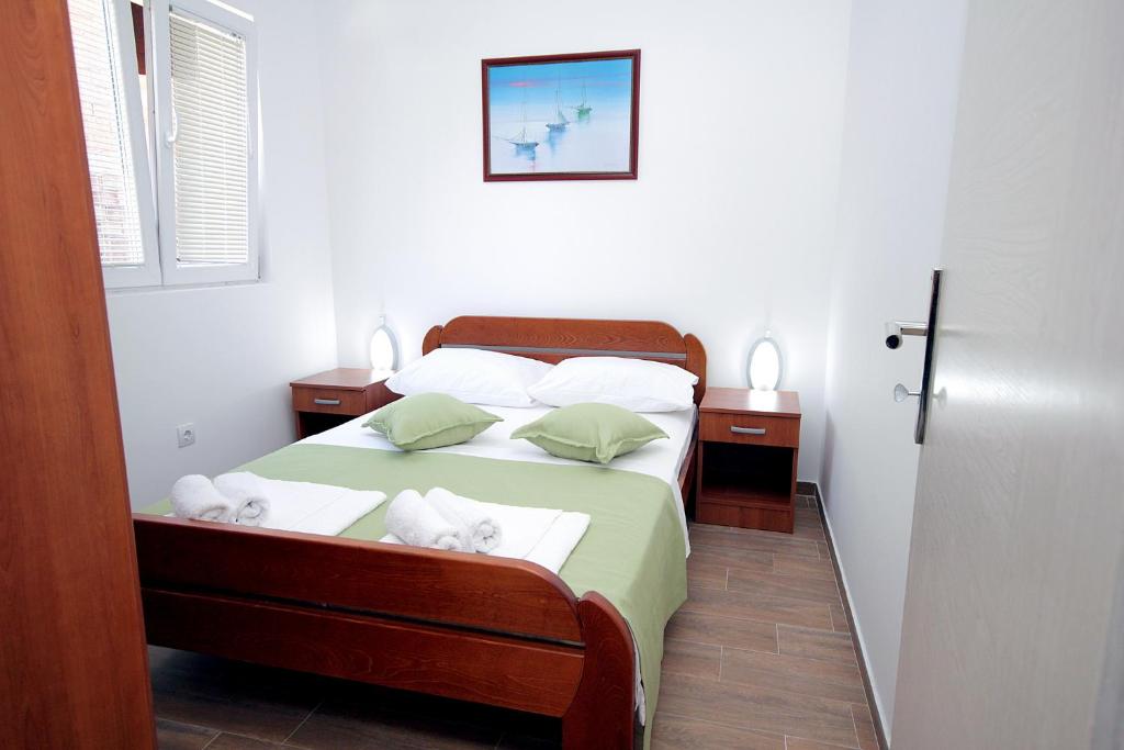 een slaapkamer met een bed met 2 kussens en handdoeken bij Apartments Centar Sutomore in Sutomore