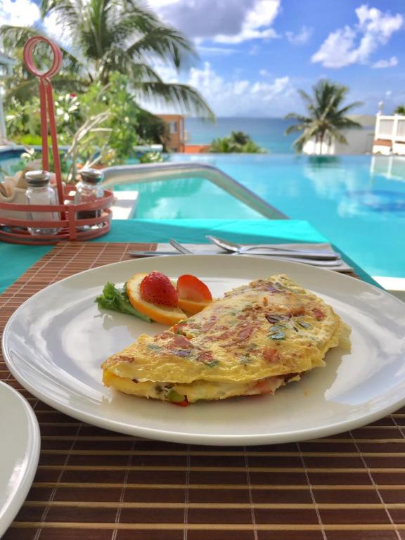 a white plate with an omelet and fruit on a table at La Vista Resort in Simpson Bay