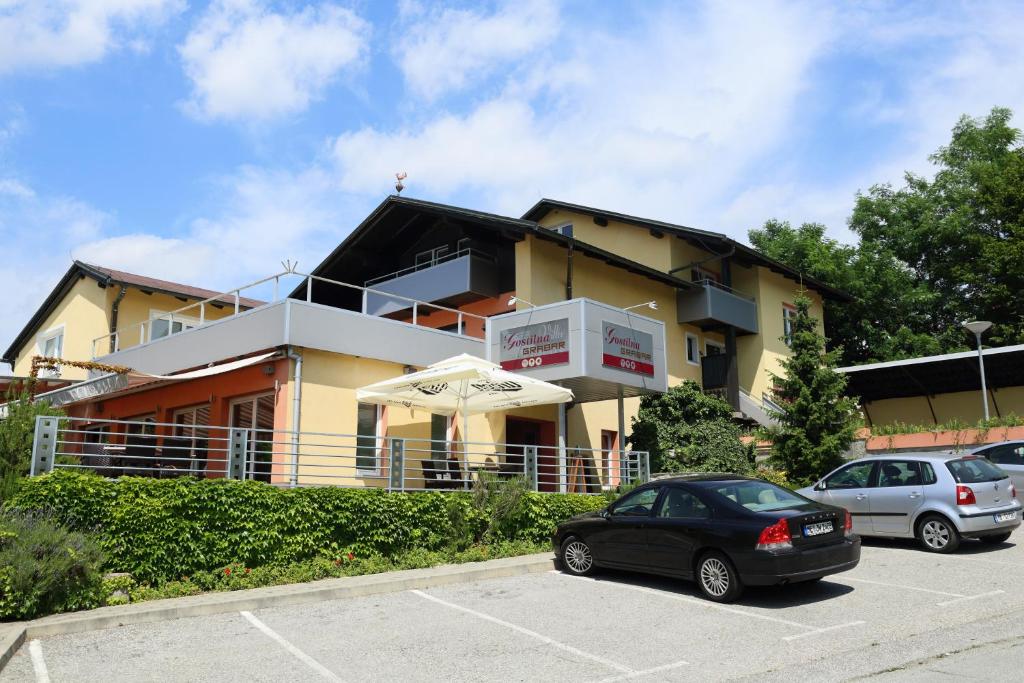 un bâtiment avec deux voitures garées dans un parking dans l'établissement Sobe Grabar, à Ptuj