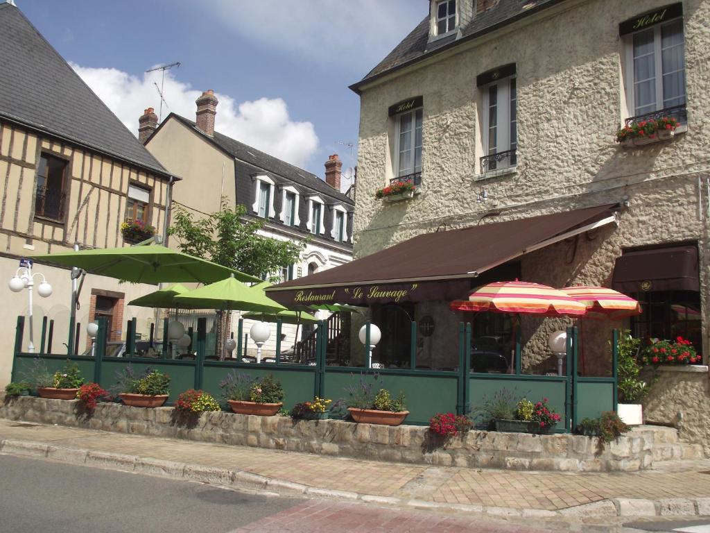 a restaurant with umbrellas on the side of a building at Le Sauvage in Château-Renard