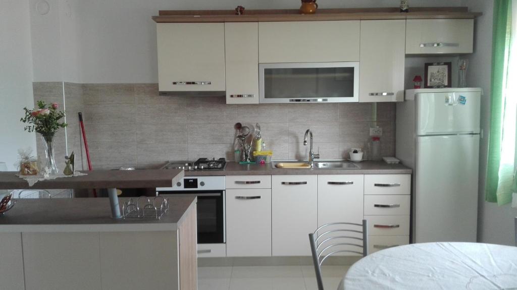 a kitchen with white cabinets and a white refrigerator at Apartments Branko in Veli Rat