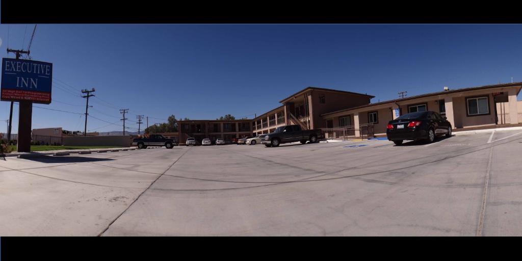 un estacionamiento con autos estacionados frente a un edificio en Executive Inn Mojave, en Mojave