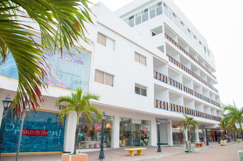 a white building with palm trees in front of it at Hotel Portofino in San Andrés