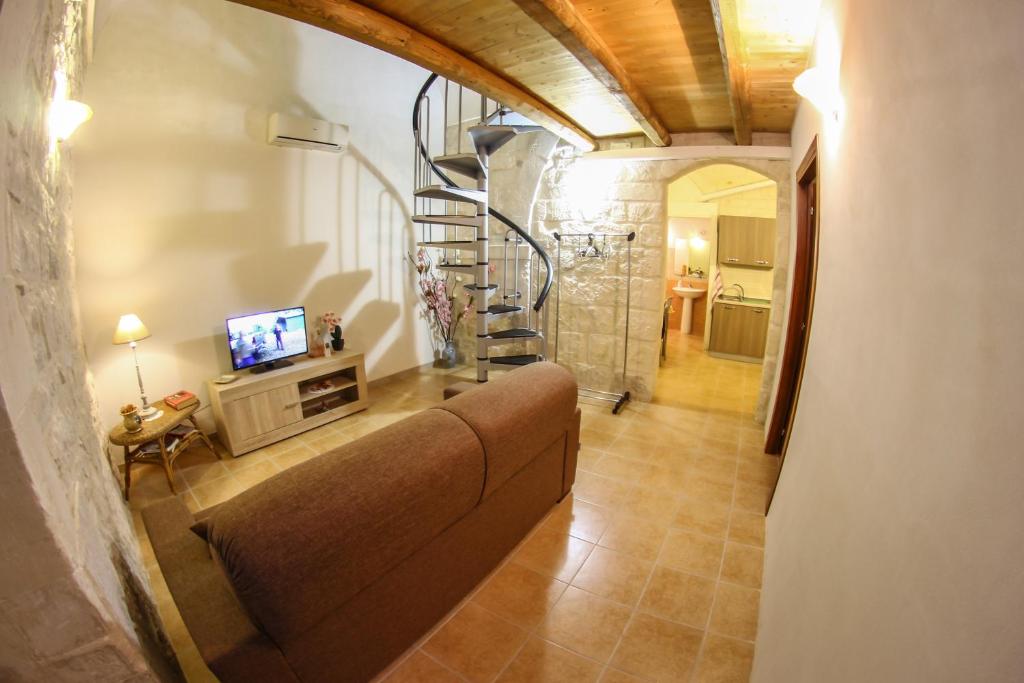 a living room with a couch and a spiral staircase at L'insula in Scicli