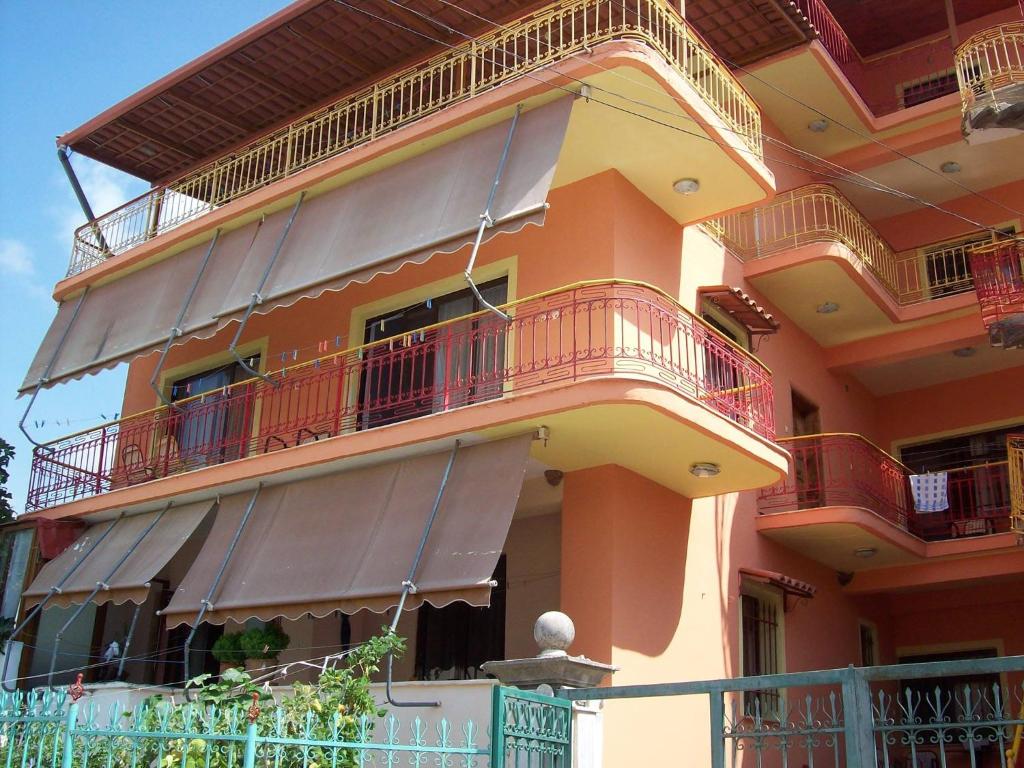 a large orange building with balconies and a fence at Apartamente plazhi in Sarandë