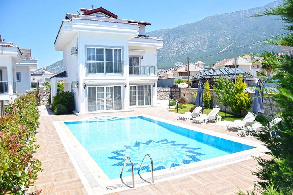 a villa with a swimming pool in front of a house at Villa Belvedere in Fethiye