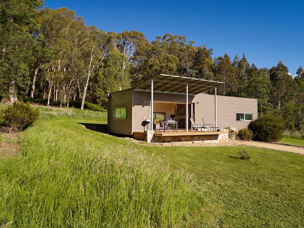 a small cabin with a roof on a grass field at The Buckland Studios in Porepunkah