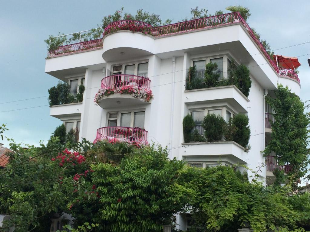 een wit gebouw met rode balkons en bloemen bij Guesthouse JANA in Pomorie