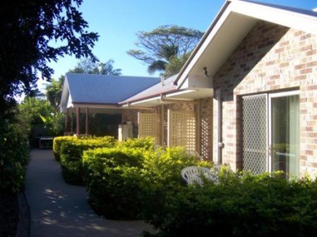 uma casa de tijolos com arbustos à frente em Redland Bay Motel em Redland Bay