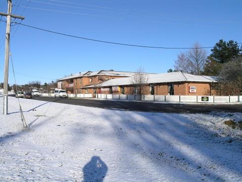 a shadow of a person standing on a snow covered street at Snowgate Motel + Apartments in Berridale