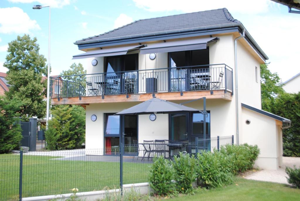 a white house with a balcony and an umbrella at Gîte De Charme in Colmar