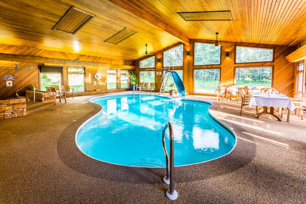 a large swimming pool in a room with a table at Rustlers Lodge in Sundre