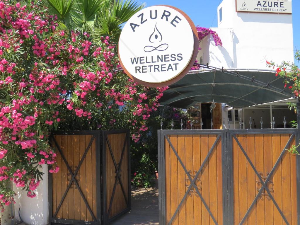 a wellness retreat sign over a gate with pink flowers at Azure Wellness Retreat in Turgutreis