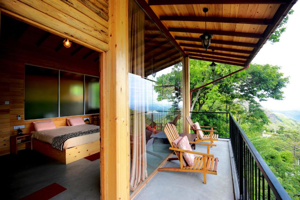einen Balkon eines Hauses mit einem Bett und Stühlen in der Unterkunft Country Homes in Ella