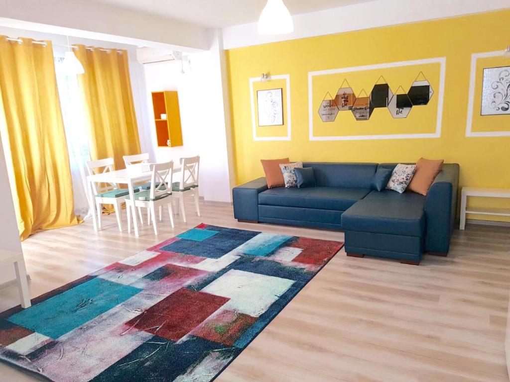 uma sala de estar com um sofá azul e uma mesa em Fundeni Apartments em Bucareste