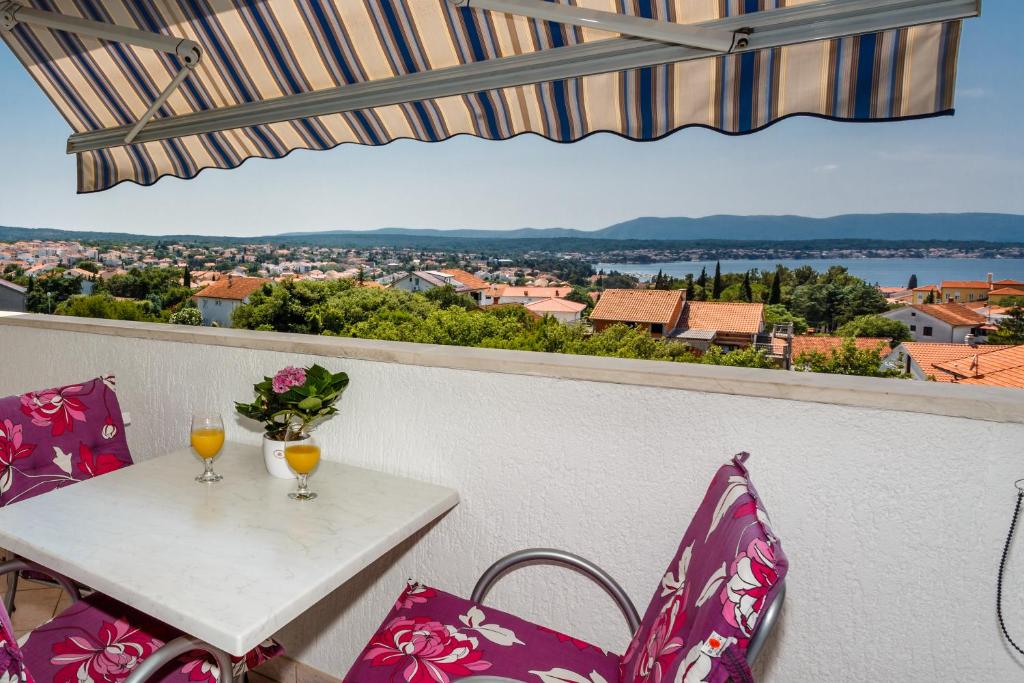 a table with two wine glasses on a balcony with a view at Apartment Luna in Malinska