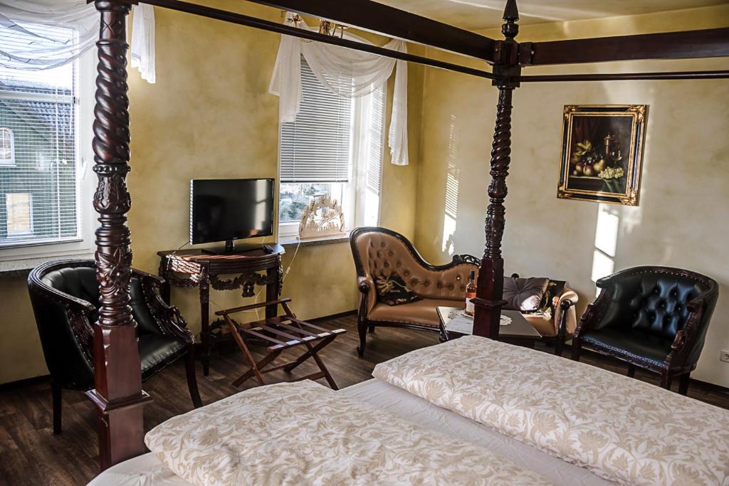 ein Schlafzimmer mit einem Bett und Stühlen sowie einem TV in der Unterkunft Märchenpension Rotkäppchen und der Wolf in Großwaltersdorf