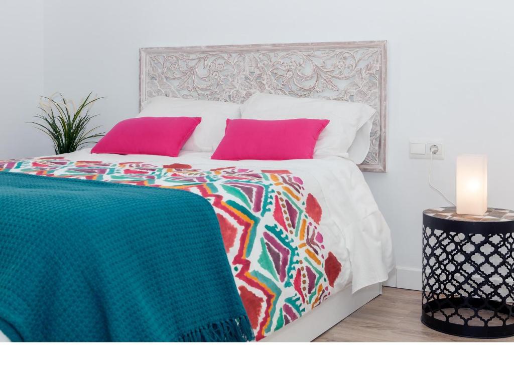 トレドにあるApartamentos Rey Moroのピンクと緑の枕とキャンドル付きのベッド