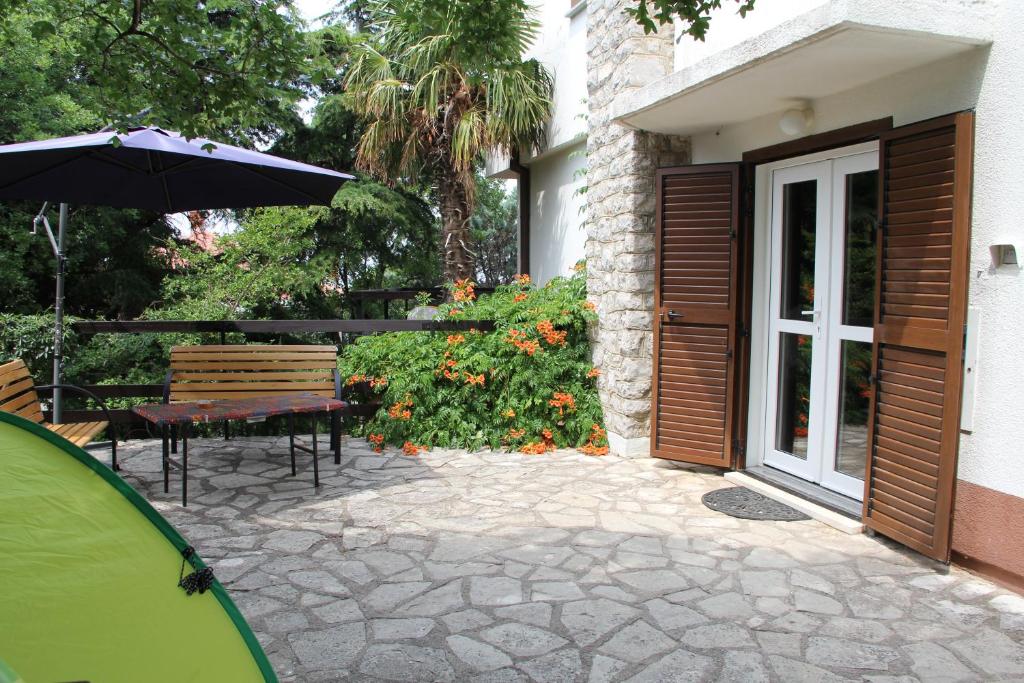 un patio con sombrilla, mesa y sillas en Holiday Home Luznar, en Klenovica