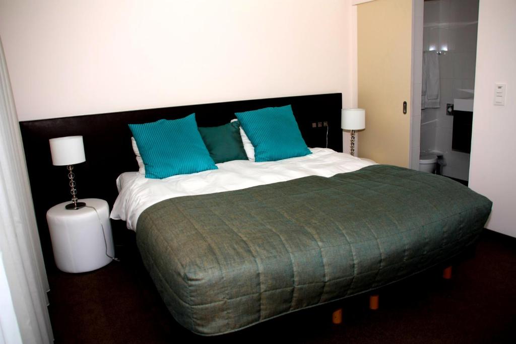 een slaapkamer met een groot bed met blauwe kussens bij Hotel Malpertuus in Riemst
