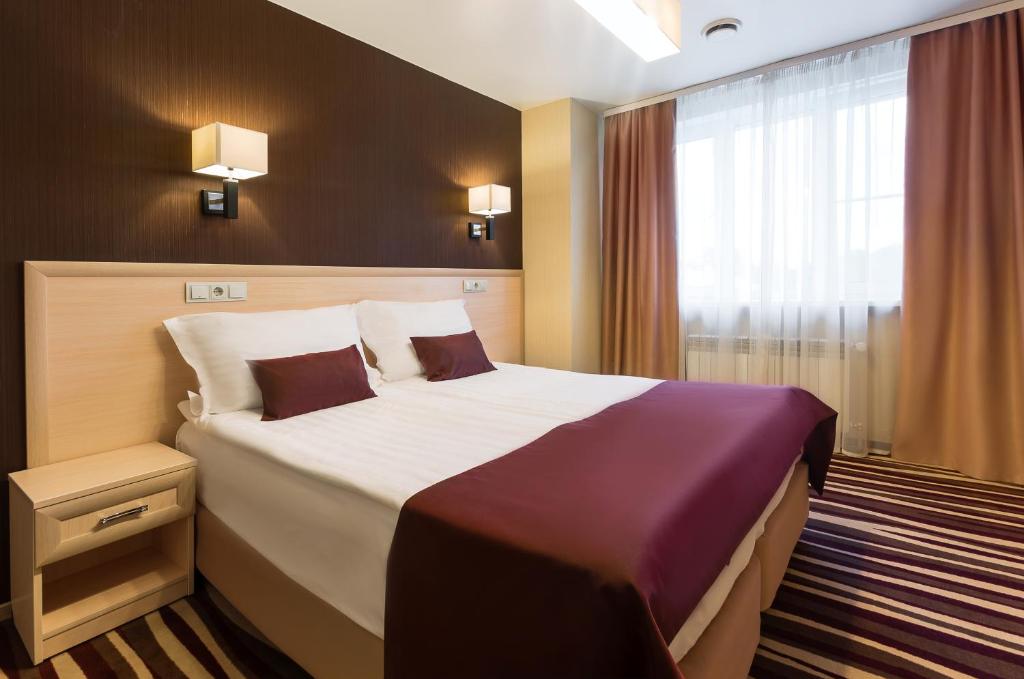 ヴォロネジにあるドガ ライト ホテルの大きなベッドと窓が備わるホテルルームです。