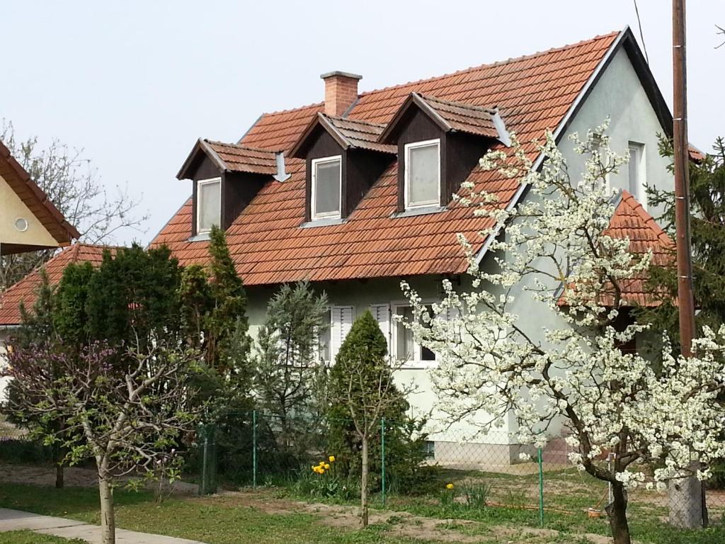 una casa con techo rojo y árboles en flor en Gyula-tanya Vendégház, en Csongrád