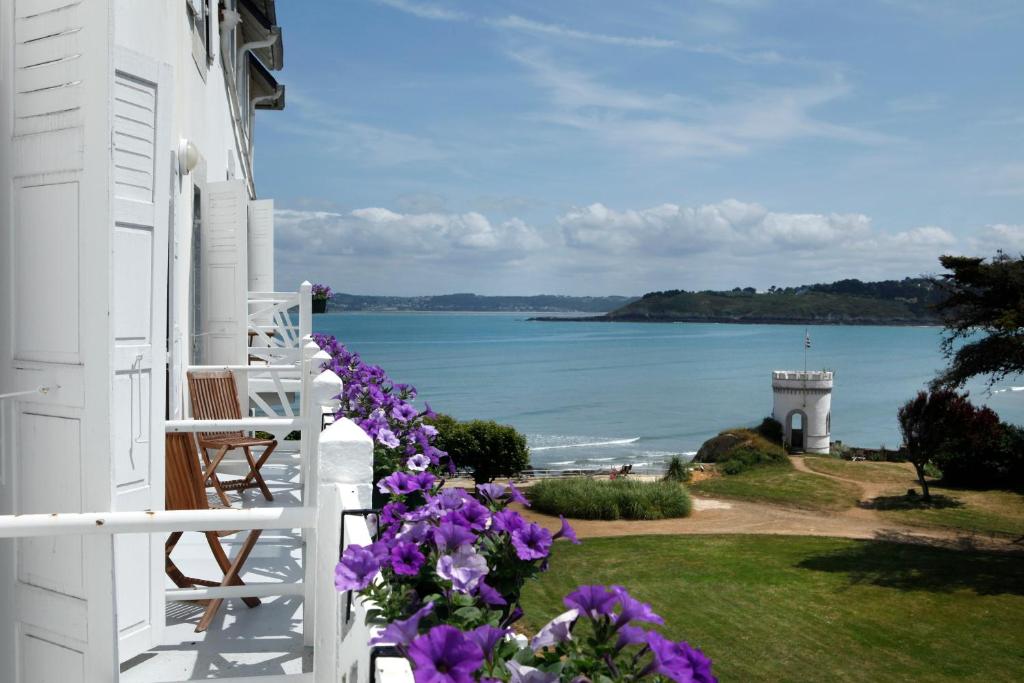 a white house with purple flowers and a lighthouse at Le Grand Hotel des Bains & Spa - Bretagne in Locquirec