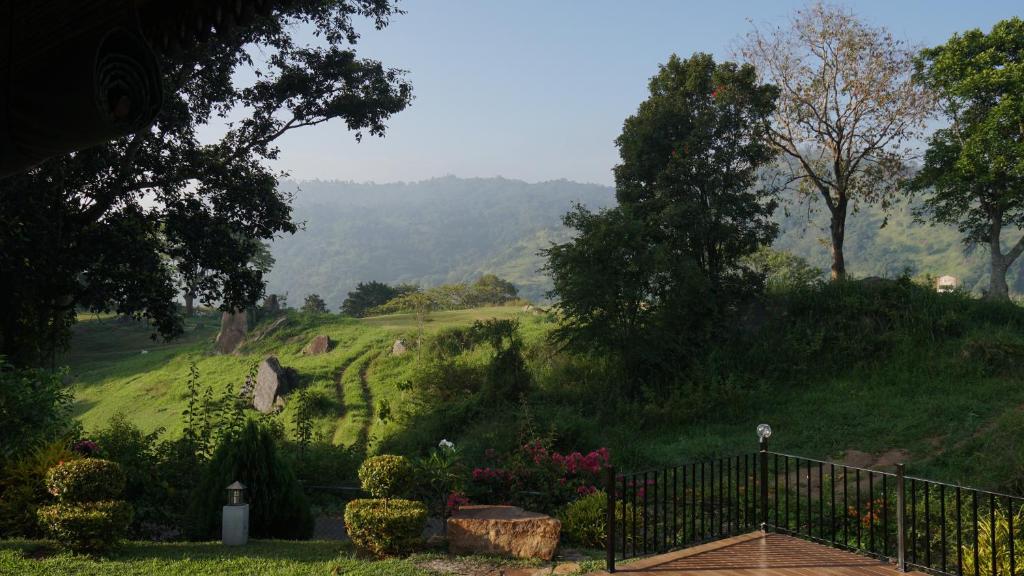 un jardín con una valla y una colina con césped en Villa Tee Four, en Digana