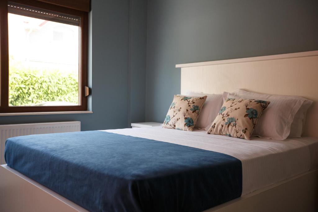 a bedroom with a bed with a blue blanket and a window at Bliss Residence - Aquamarine in Constanţa
