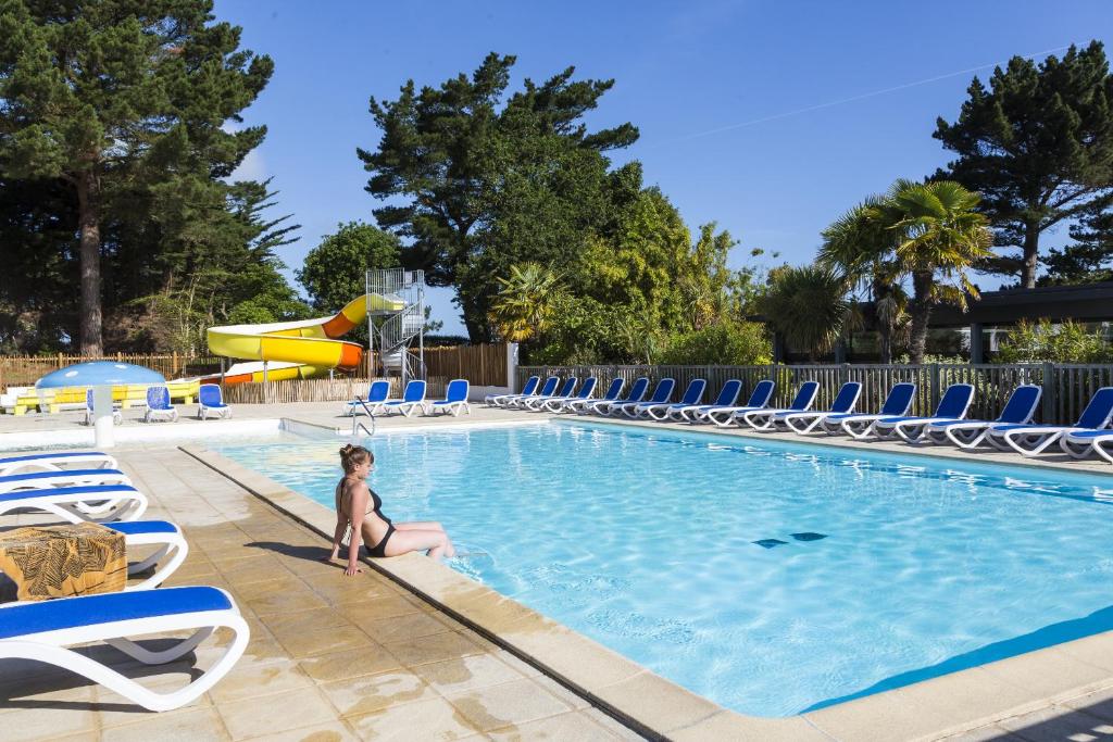 PleubianにあるDomaine Résidentiel de Plein Air Odalys Le Port de la Chaineの若い女の子がリゾートのプールに座っている