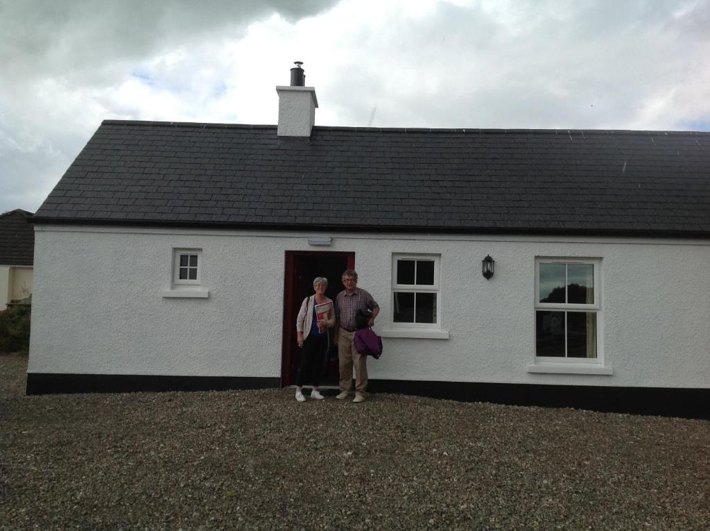 dos personas de pie en la puerta de una casa blanca en Derg Cottage, en Strabane