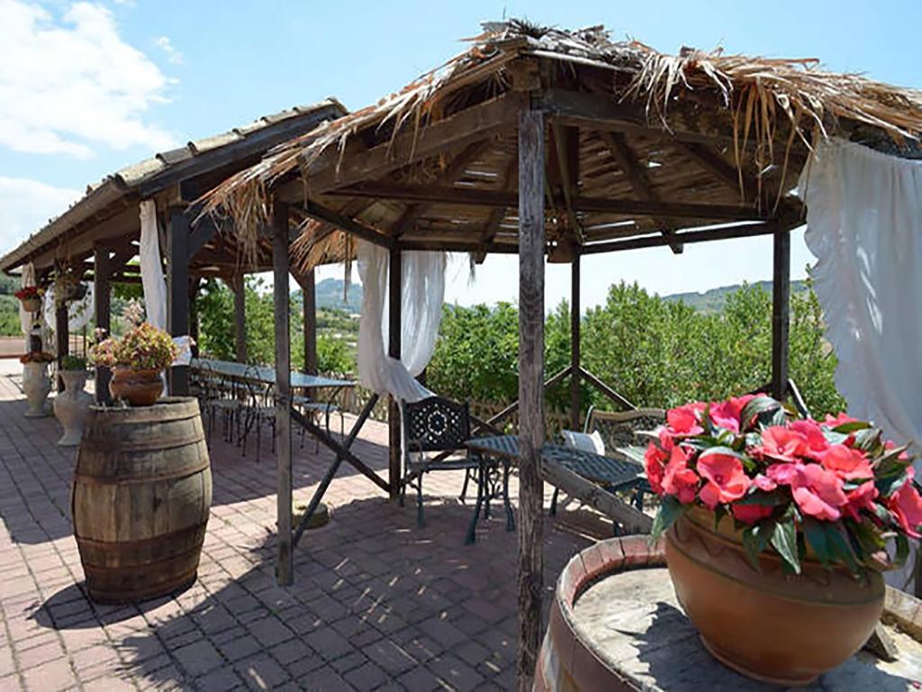 un patio con padiglione con tavoli, sedie e fiori di Agriturismo Due Ganèe a Agrigento