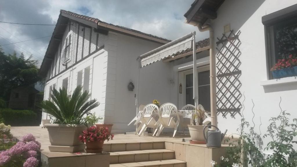 a white house with two chairs and a table at Chambres d'Hôtes Le Perdigon in Estang