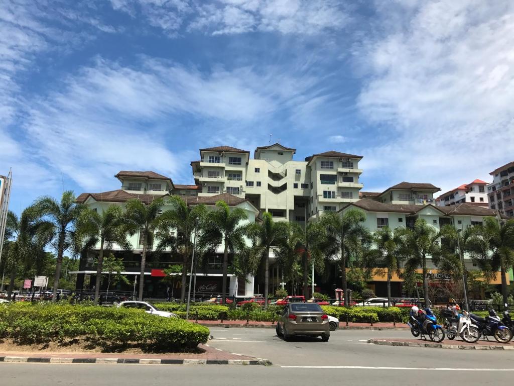 ein Parkplatz mit einem Gebäude mit Palmen und Autos in der Unterkunft Nusantara Mattwaddien M.S in Kota Kinabalu