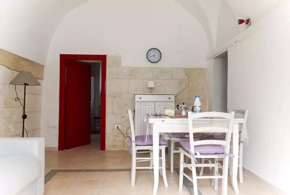 uma cozinha com mesa e cadeiras e um relógio na parede em Barco Apartment em Ostuni