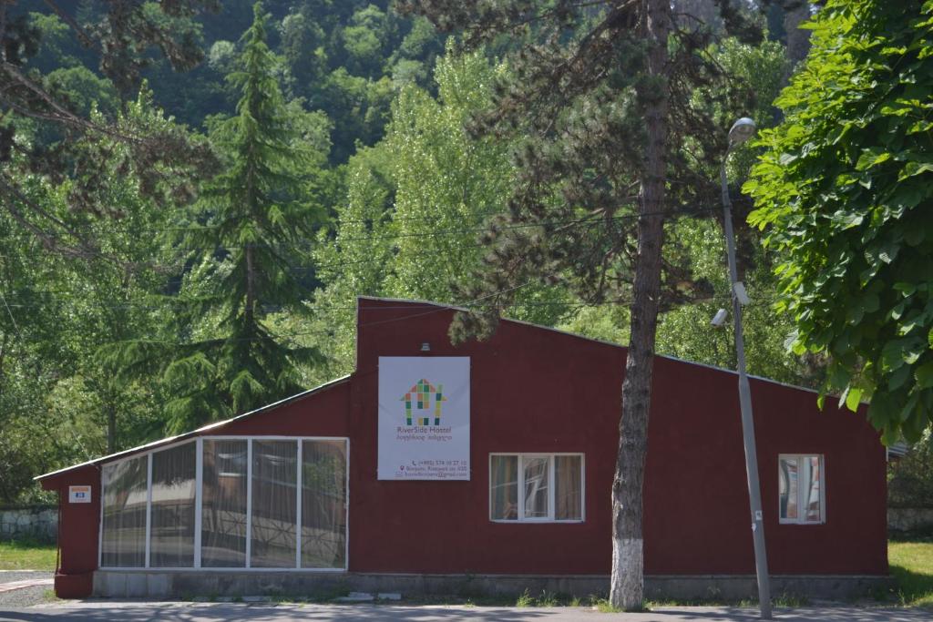 a red building with a sign on the side of it at RiverSide Hostel Borjomi in Borjomi