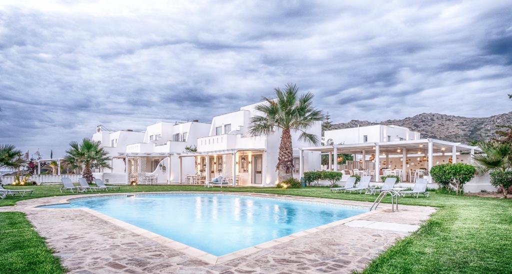 a large white house with a swimming pool and palm trees at Orkos Beach Hotel in Mikri Vigla