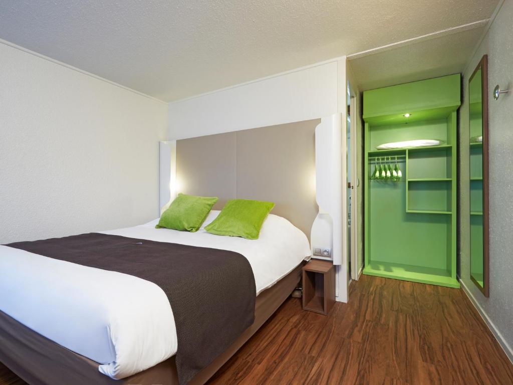 una camera da letto con un grande letto con accenti verdi di Campanile Le Mans Est a Le Mans